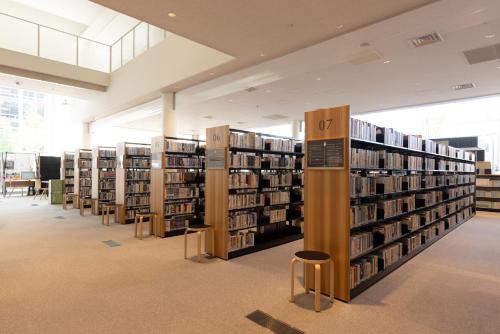 a library with several stacks of books and stools at Tsukino HOTEL in Sakata
