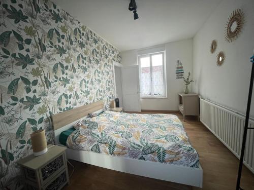 a bedroom with a bed with a floral wallpaper at Au gîte des Frangines in Grand-Fort-Philippe