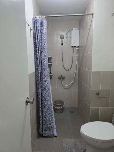a bathroom with a shower curtain and a toilet at Cozy Studio Long Stays Welcome in Biñan