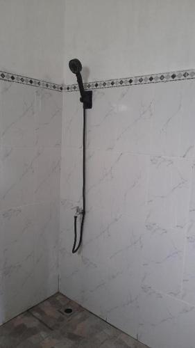 a shower in a bathroom with a white wall at Bali Home Taksu in Jatiluwih