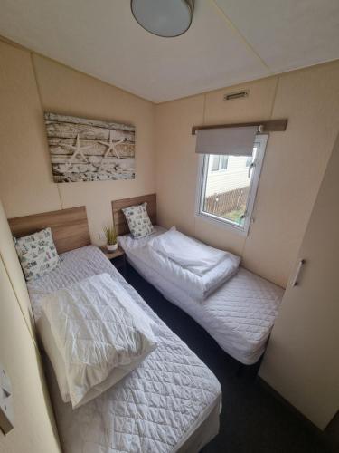 two beds in a small room with a window at Spacious accomodation 188 Unity Beach sleeps 6 Centrally located Pet friendly Pets Stay Free in Brean