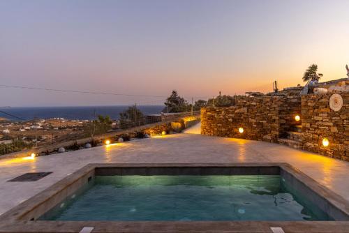 a swimming pool on top of a building with the sunset at Marilias cycladic home in Agios Fokas