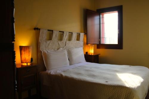a bedroom with a bed with white sheets and a window at CORTE STELLATA Il Grano Lodging in Bondeno