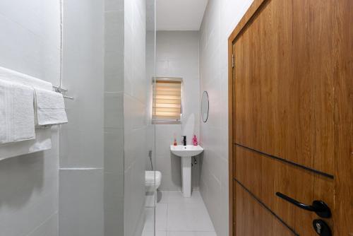 a bathroom with a toilet and a sink and a wooden door at The Zenith Palace in Lekki