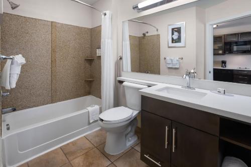 a bathroom with a sink and a toilet and a bath tub at Candlewood Suites Norfolk Airport by IHG in Norfolk