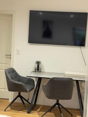 two chairs and a table with a television on a wall at Studio My Home in Brig