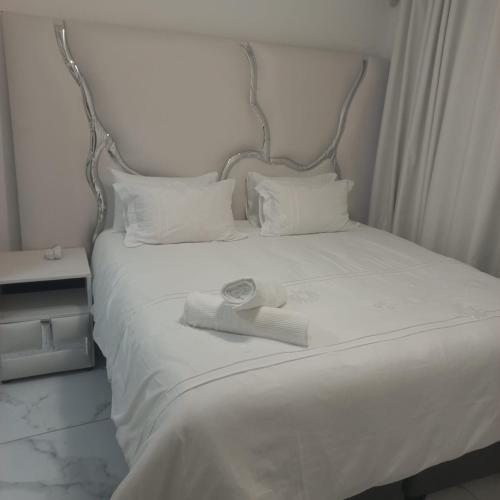 a white bed with a headboard and two towels on it at Comfort Retreat in Roodepoort