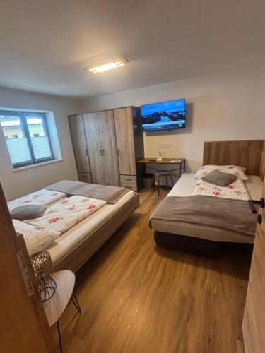 a bedroom with two beds and a table and a tv at Appartement Steinbergrose in Leogang