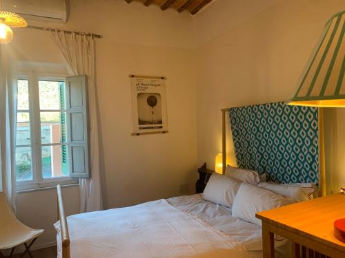 a bedroom with a bed and a desk and a window at La Meridiana in Vicopisano