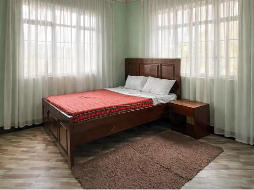 a bed sitting in a room with windows at Oltare Safari Homestay in Makuyuni
