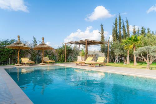 a swimming pool with chairs and umbrellas in a yard at Maison soli Marrakech in Bou Khaoua