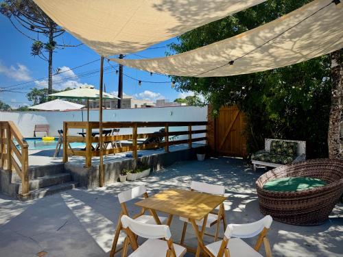 a patio with a table and chairs and a pool at Pousada Pássaros Park in Itapoa
