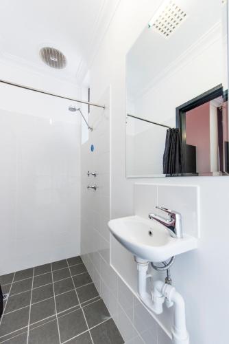 a white bathroom with a sink and a shower at Billabong Backpackers Resort in Perth