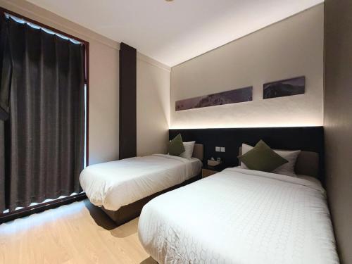 two beds in a room with a window at Asphodel Inn - Newly Renovated in Singapore
