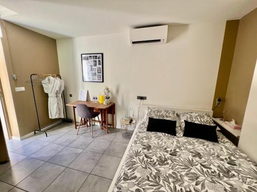 ein Schlafzimmer mit einem Bett, einem Tisch und einem Schreibtisch in der Unterkunft Studette de 17m2 avec parking privé gratuit Climatisation et petite cuisine in Menton
