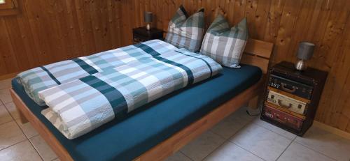 a bed with a blue and white blanket and pillows at Wohnung in Reichenbach im Kandertal in Reichenbach