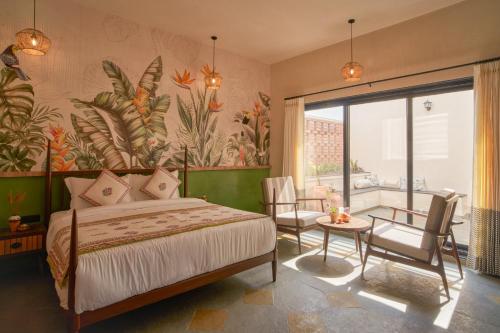 a bedroom with a bed and a table and chairs at Niwasa - A Luxury Boutique Stay, Udaipur in Udaipur