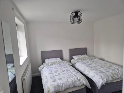 a bedroom with two beds and a mirror at Brigg new build home in Brigg