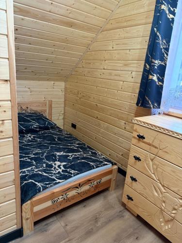 a bedroom with a bed in a wooden cabin at Domek w górach in Załuczne