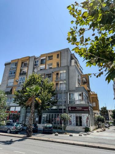 a tall building on a city street with a tree at ALEXANDER Rooms & Apartments in Durrës