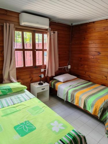 two beds in a room with wooden walls and windows at Hogape in Posadas
