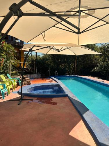a swimming pool with an umbrella and a swimming pool at Yellow Submarine Hostal in Poneloya
