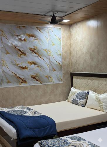 a bedroom with two beds and a painting on the wall at Hotel Al Mehraj in Mumbai