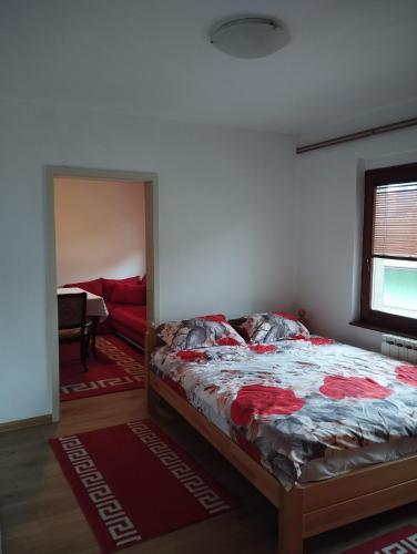 a bedroom with a bed and a living room at Apartmani Emir in Visoko
