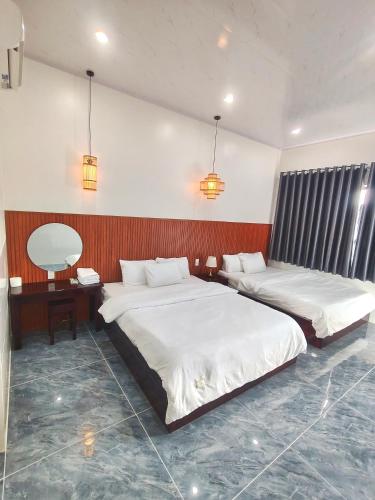 a bedroom with two beds and a table and a mirror at Cherry House villa in Hà Tiên
