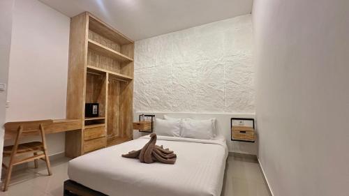 a bedroom with a white bed with a wooden wall at Bukawa Residences Balangan in Jimbaran