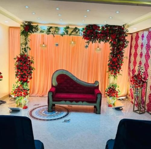 a couch in front of a stage with flowers at Lallan Top Hotel in Unnāo