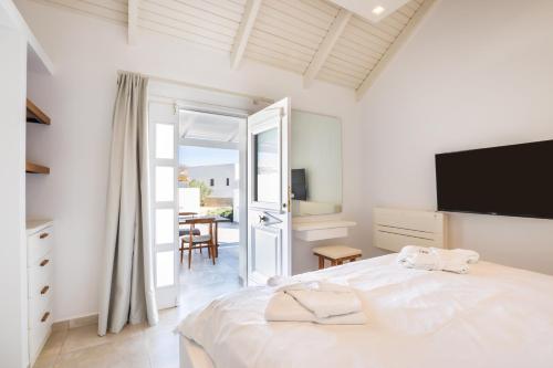 a bedroom with a bed with a television and a table at Manos Villas in Karpathos