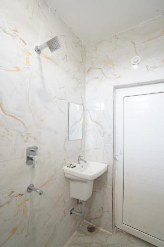 a white bathroom with a sink and a mirror at Hotel Shubh Bodhi in Bodh Gaya