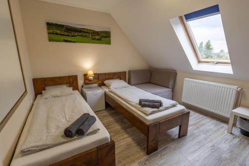 a small room with two beds and a window at Forrás Panzió és Apartman in Orfű