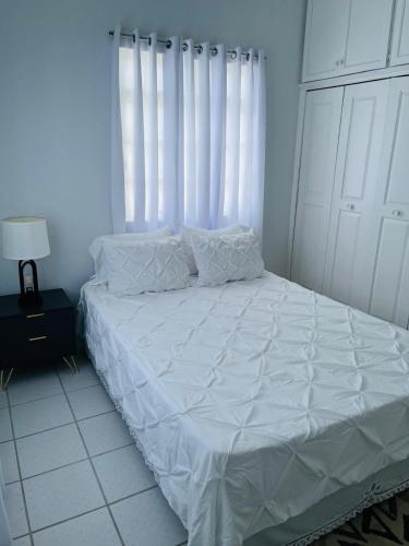 a white bed in a room with a window at Lyn Tropical Getaway in Port-of-Spain