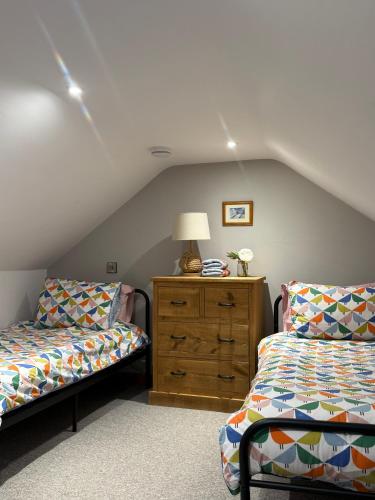 a attic bedroom with two beds and a dresser at Y Beudy Bach in Llanfor