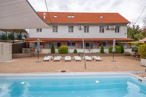 a swimming pool in front of a house at Forrás Panzió és Apartman in Orfű