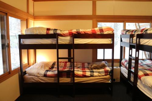 two bunk beds in a room with a window at Kamoshika Cottage Hakuba in Hakuba
