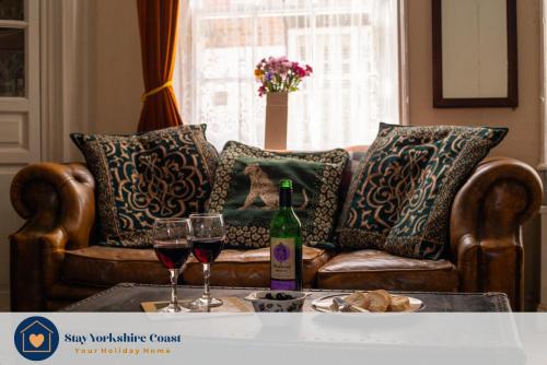 a couch with two glasses of wine on a table at Half Moon House - Timeless Charm with Sea Views in Scarborough
