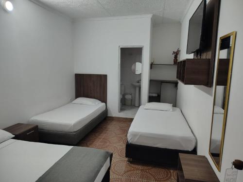 a small room with two beds and a television at Hotel Cascada in Ríohacha