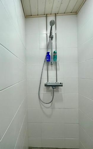 a shower with a hose in a white tiled bathroom at Centerpoint Imatra in Imatra