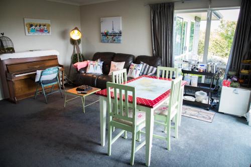 a living room with a table and chairs and a piano at Waitomo Orchard Estate B&B in Otorohanga