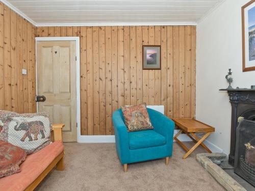 a living room with a blue chair and a fireplace at Tinakori in Staithes