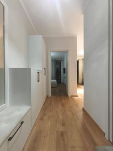 a kitchen with white cabinets and a hard wood floor at Red School Central Apartment New Bazaar in Tirana