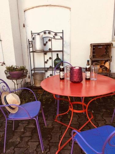 a red table with two chairs and two bottles on it at Ferienwohnung Eberhard in Schwäbisch Gmünd