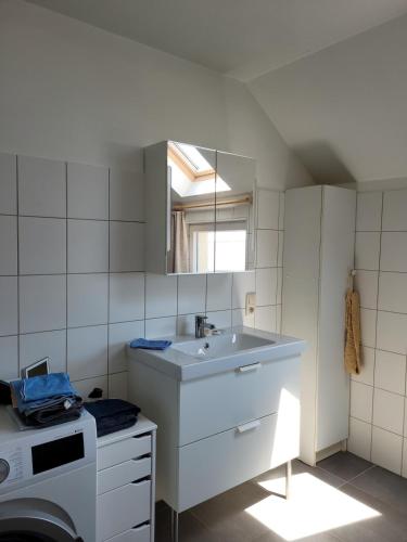 ein weißes Badezimmer mit Waschbecken und Spiegel in der Unterkunft Apartment Libramont in Libramont