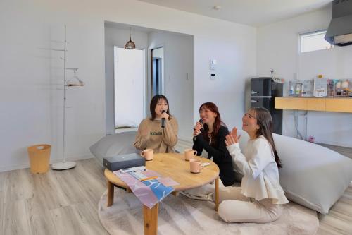 three women sitting around a table in a living room at 「淡路島一棟貸宿　野うさぎ 」高台から海を望む貸別荘！2023年新築離れの素泊まり in Noda