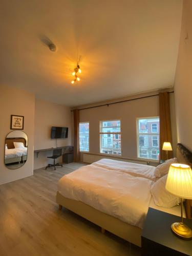 a bedroom with a large white bed and windows at Hotel La Noire - Delft City Centre in Delft