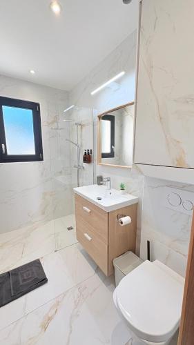 a white bathroom with a toilet and a sink at Les Oliviers climatisés parking recharge électrique in Arles
