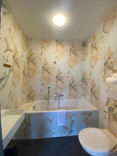 a bathroom with a tub and a toilet and a sink at Hotel La Noire - Delft City Centre in Delft